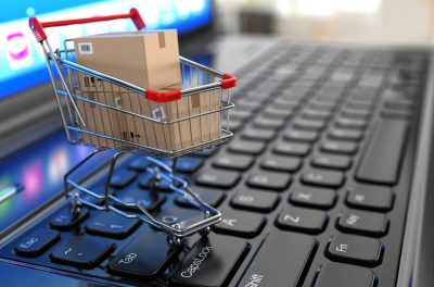 E-commerce. Shopping cart with cardboard boxes on laptop. 3d